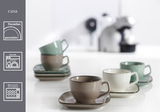 Verschiedene Kaffeetassen der Serie Casa in Grau, Beige und Grün auf quadratischen Untertassen, aus Porzellan, spülmaschinen- und mikrowellengeeignet, seitliche Perspektive.