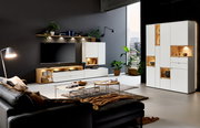 Moderne Wohnzimmermöbel mit weißem Highboard, Sideboard und Wandboard, LED-Beleuchtung, Pflanzen und Dekorationen, seitliche Perspektive.