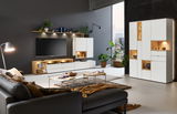 Moderne Wohnzimmermöbel mit weißem Highboard, Sideboard und Wandboard, LED-Beleuchtung, Pflanzen und Dekorationen, seitliche Perspektive.