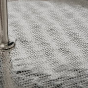Nahaufnahme einer strukturierten, silbernen Oberfläche mit einem Metallstab, perspektivisch von der Seite betrachtet.