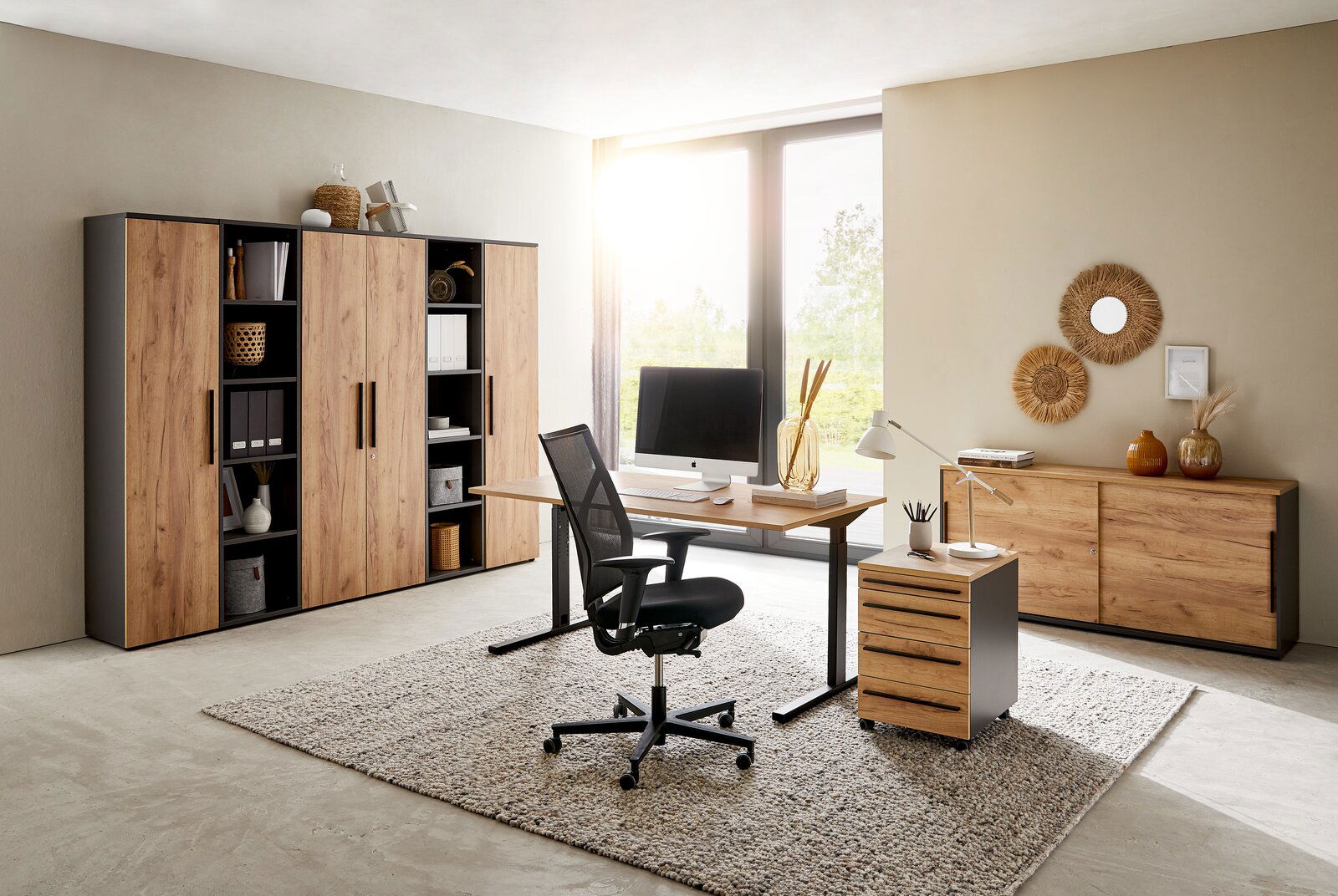 Novel Aktenschrank 5OH schmal RENTON Modernes Büro mit Holzmöbeln, bestehend aus einem Schreibtisch, einem Rollcontainer und mehreren Aktenschränken. Die Perspektive zeigt den Raum von vorne mit Blick auf das Fenster im Hintergrund.