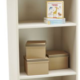Weißes Standregal mit zwei Regalböden, darauf befinden sich Bücher und braune Aufbewahrungsboxen, seitliche Perspektive