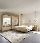 Moderne Schlafzimmeransicht mit einem großen Holzbett, flankiert von Nachttischen, und einem Kleiderschrank mit Spiegeltüren. Die Perspektive zeigt das Zimmer von vorne, mit einem weichen Teppich auf dunklem Holzboden und stilvollen Hängelampen.