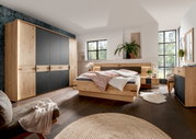 Modernes Schlafzimmer mit Holz-Kleiderschrank, Bett und Kommode in einer hellen, gemütlichen Atmosphäre. Perspektive von der linken Seite des Raumes.