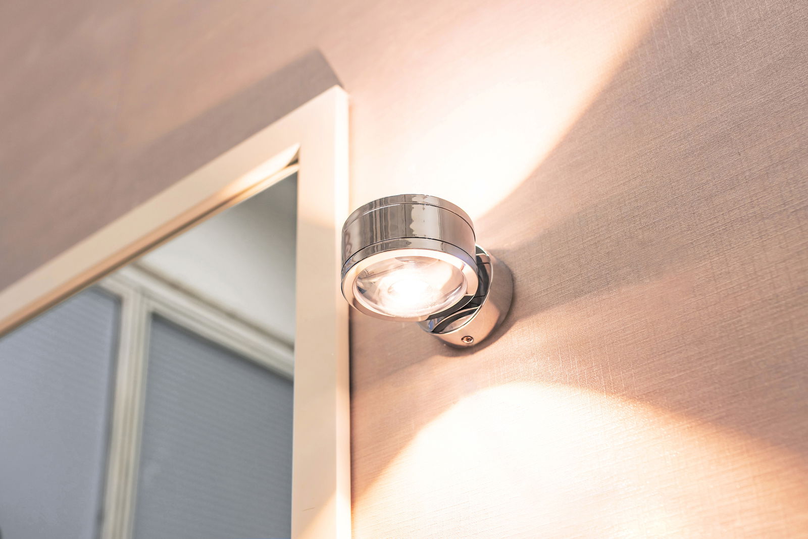 Moderne LED-Wandleuchte DUE PUNTO in Chromoptik, montiert an einer Wand, mit Up & Down Lichtstrahlung.