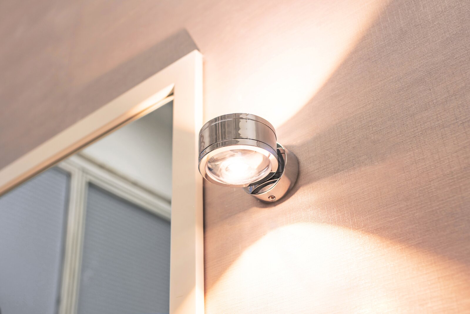 Moderne LED-Wandleuchte DUE PUNTO in Chromoptik, montiert an einer Wand, mit Up & Down Lichtstrahlung.