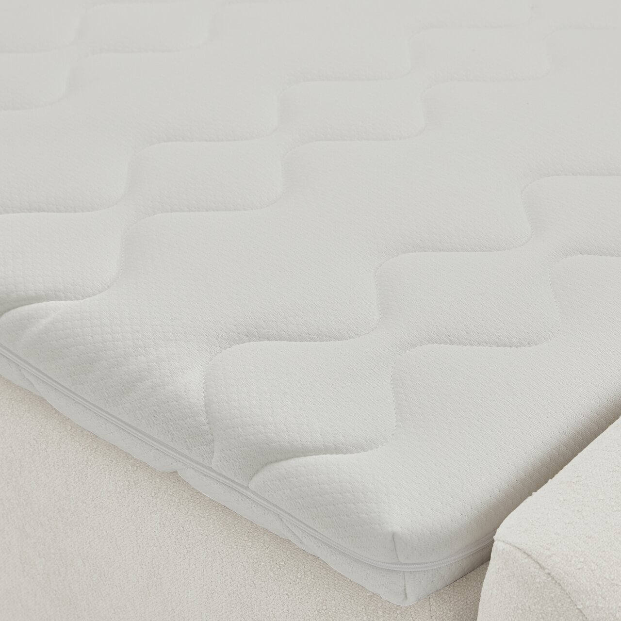 Nahaufnahme einer weißen Matratze mit wellenförmigem Muster auf einem Boxbett, seitliche Perspektive