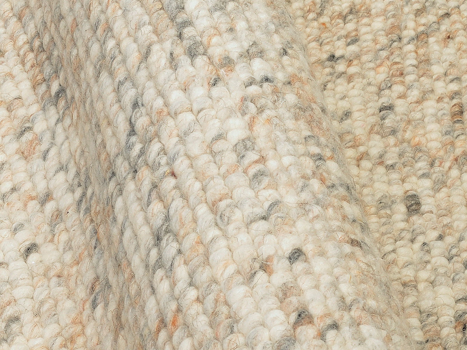 Nahaufnahme eines handgewebten Teppichs mit grober Textur in natürlichen Beige- und Grautönen, seitliche Perspektive