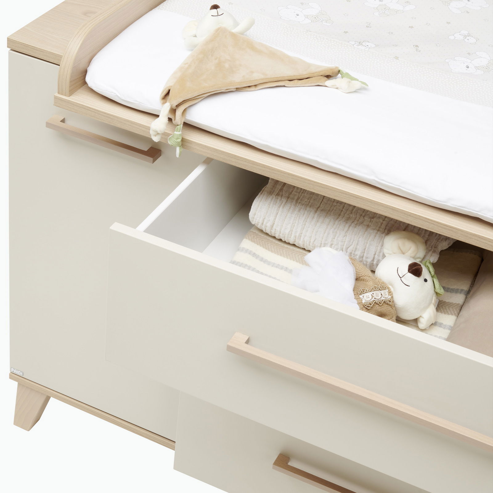 Kommode mit geöffneten Schubladen, gefüllt mit Babyartikeln, aus einer schrägen Vogelperspektive fotografiert.