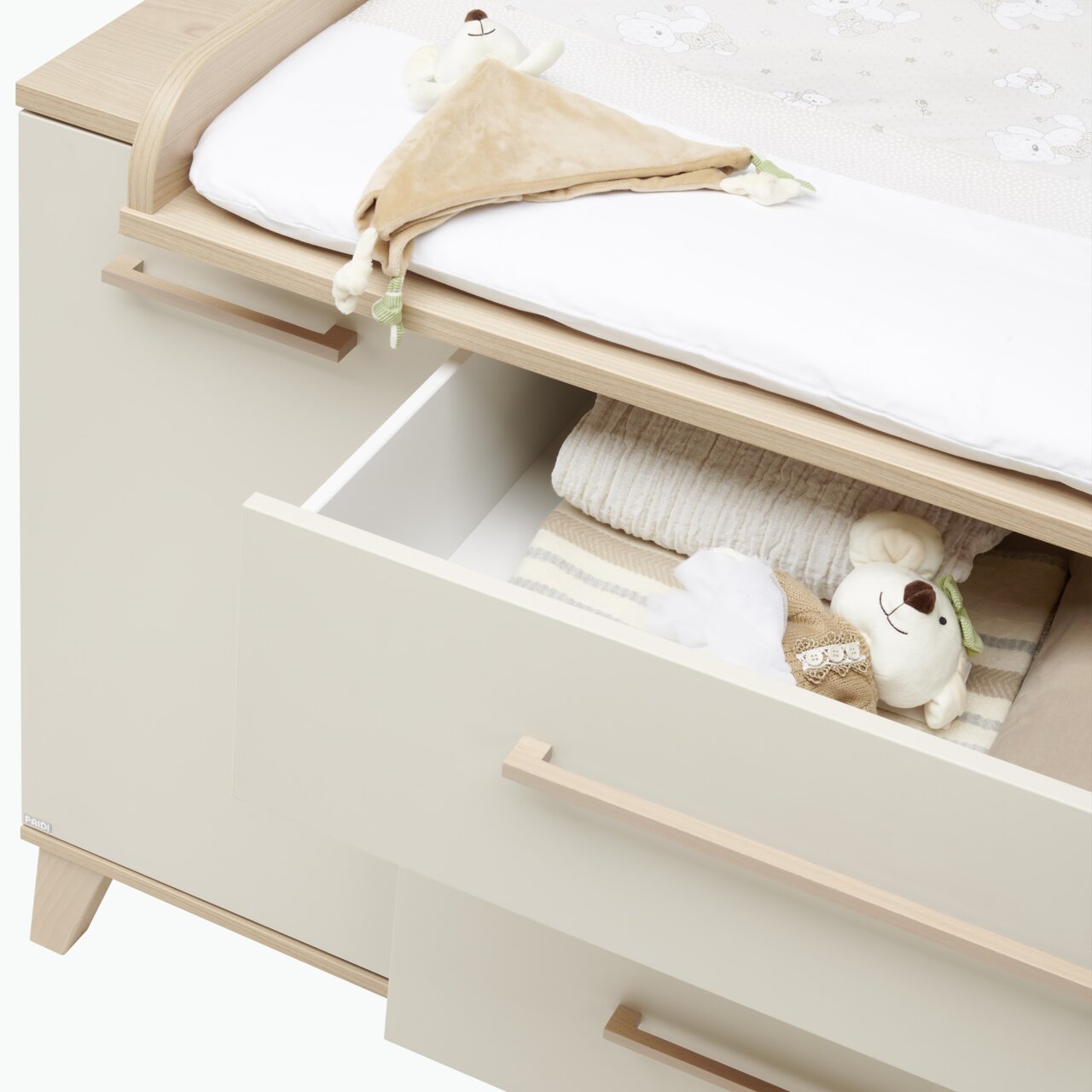 Kommode mit geöffneten Schubladen, gefüllt mit Babyartikeln, aus einer schrägen Vogelperspektive fotografiert.