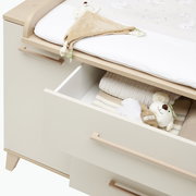 Kommode mit geöffneten Schubladen, gefüllt mit Babyartikeln, aus einer schrägen Vogelperspektive fotografiert.