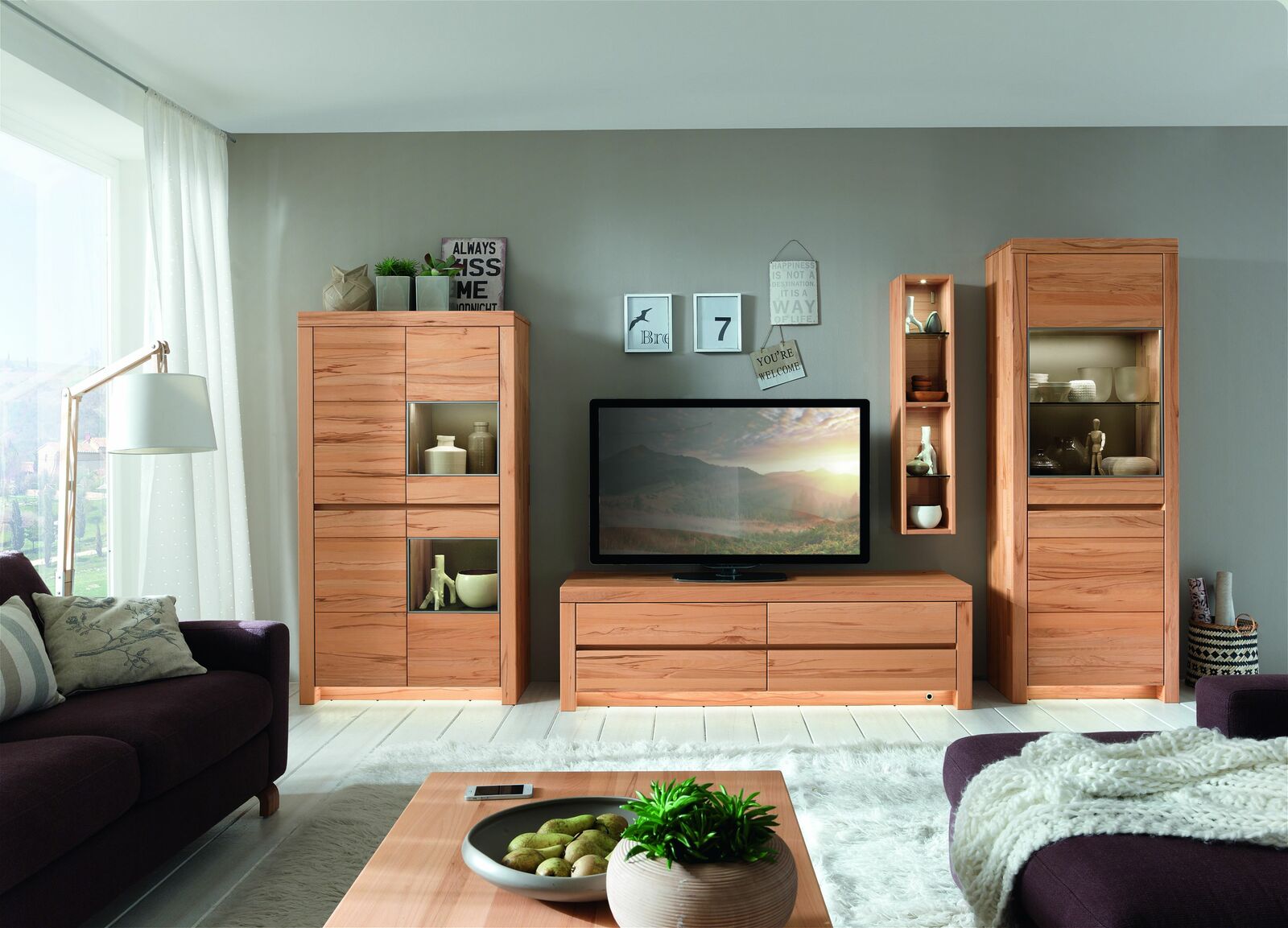 Wohnzimmeransicht mit Hängeregal, das in einem modernen, hellen Raum an der Wand montiert ist, umgeben von weiteren Möbelstücken.