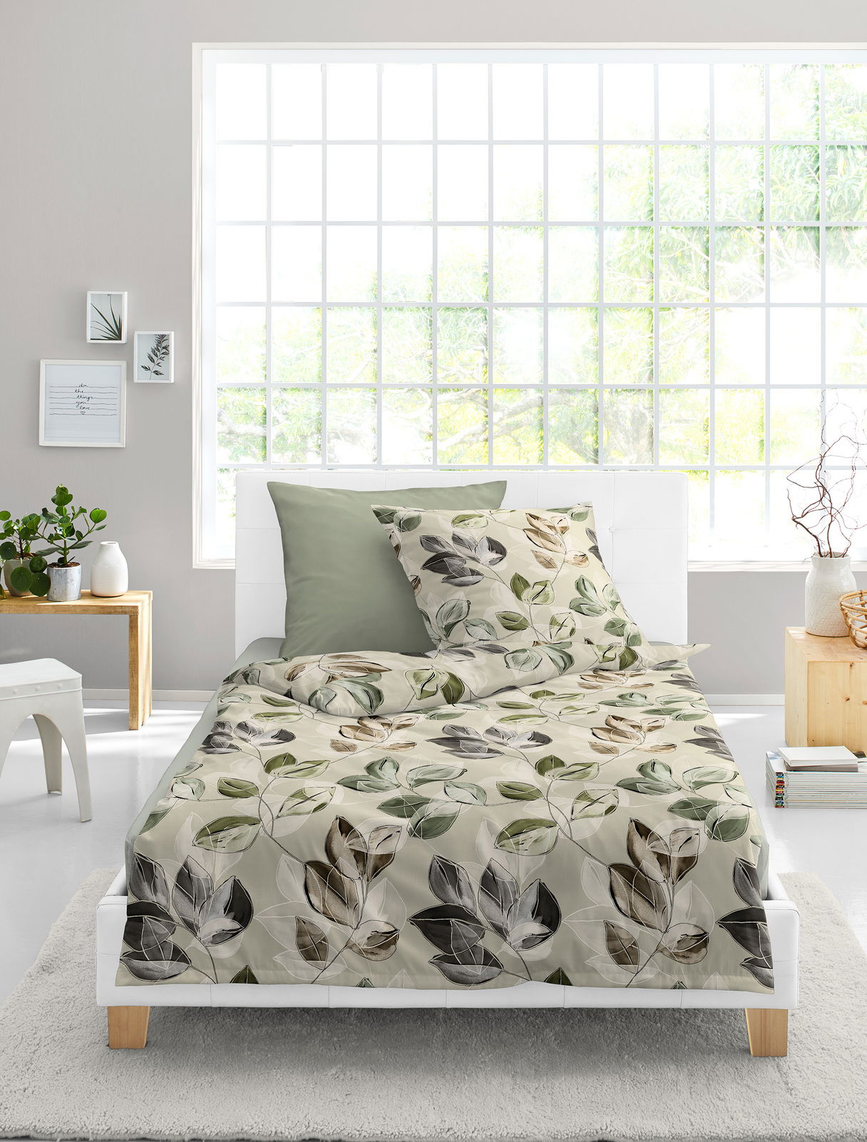 Bettwäsche-Set 155x220cm mit Blättermuster in natürlichen Farben, auf einem weißen Bett in einem hellen Raum mit großen Fenstern, aus der Vorderansicht fotografiert.