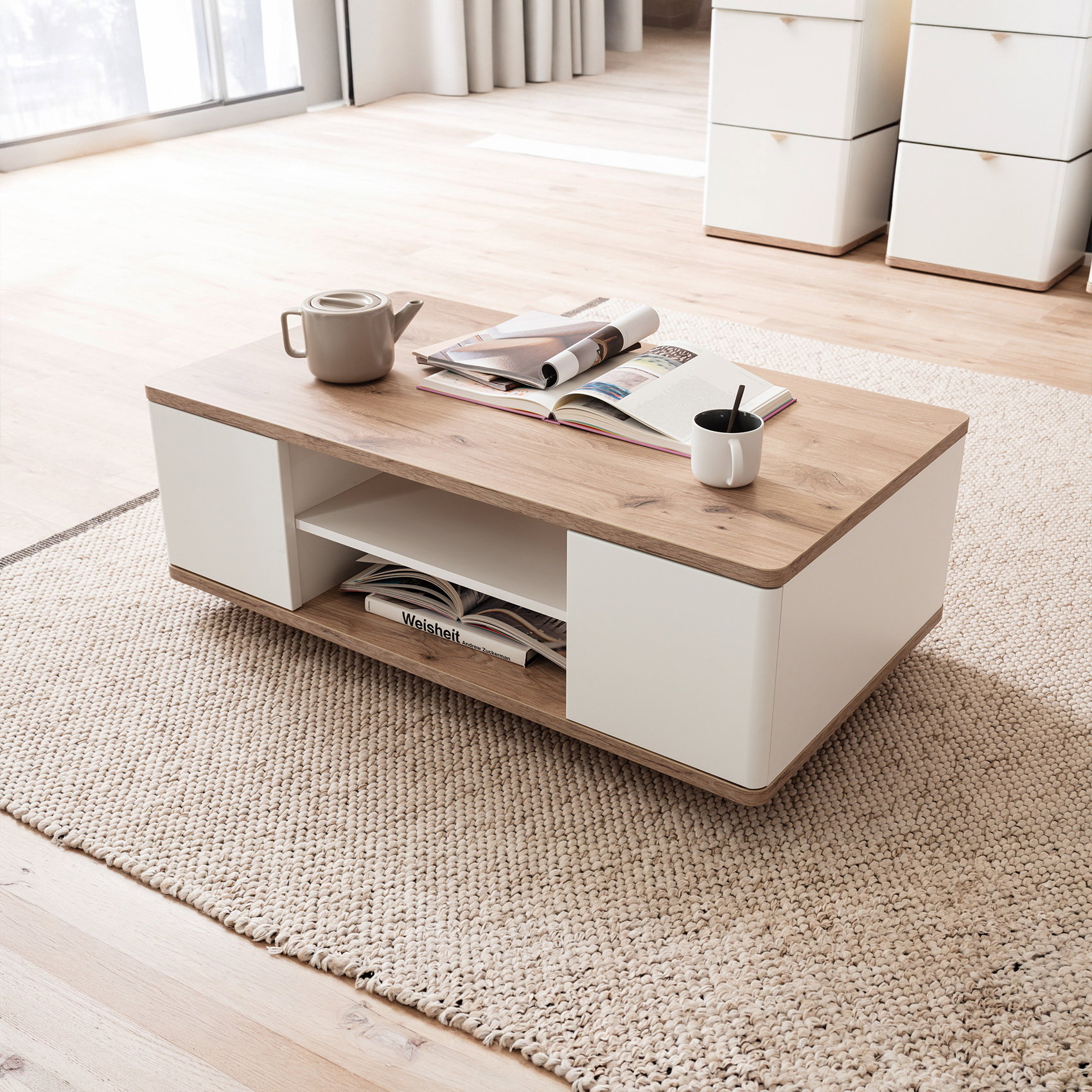Moderner Couchtisch in Holzoptik mit weißen Elementen, Deko und Tasse auf hellem Teppich im Wohnzimmer.