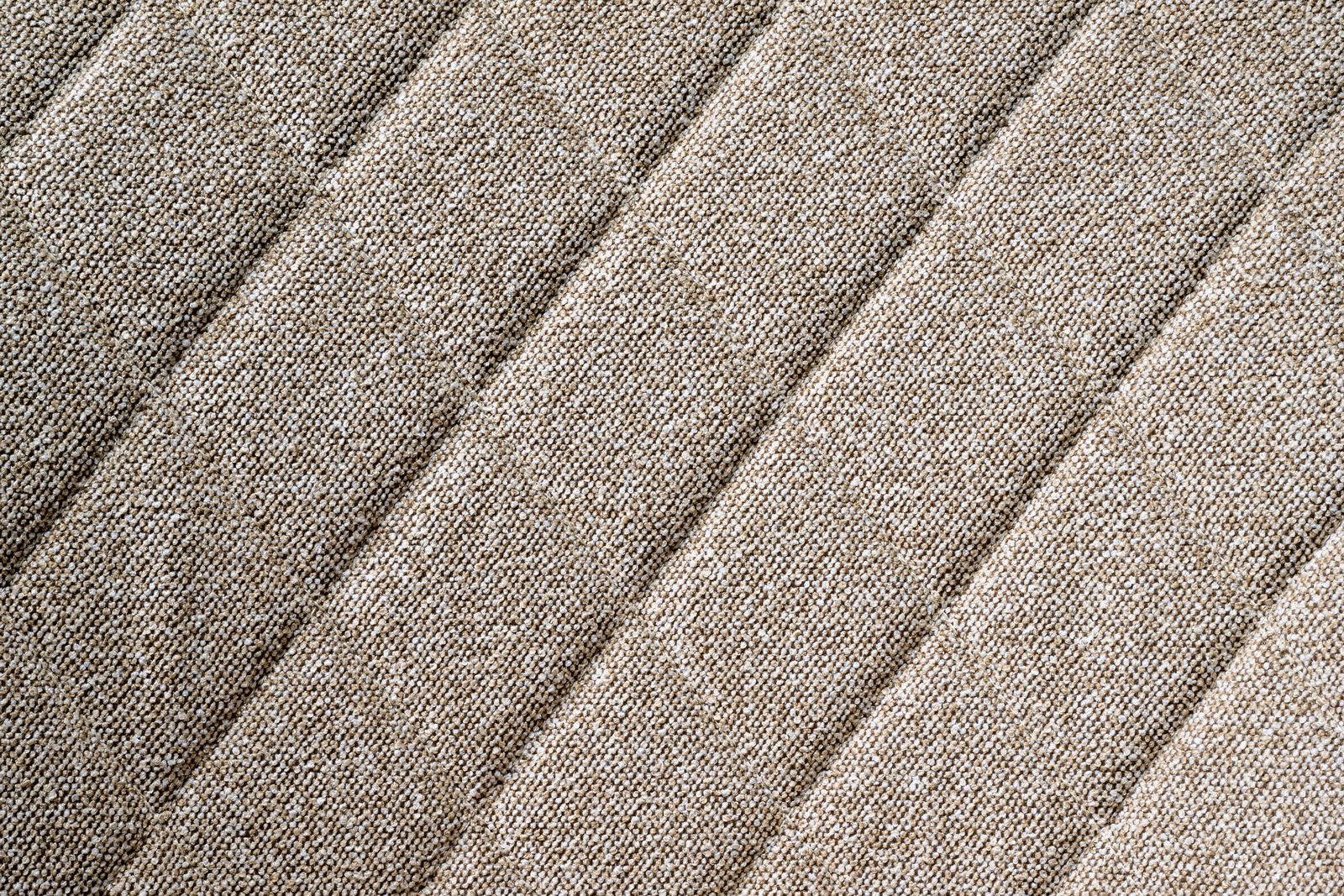 Nahaufnahme des beige strukturierten Stoffes eines Drehstuhlsitzes in diagonaler Perspektive