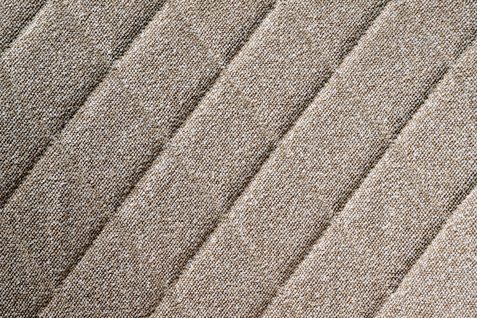 Nahaufnahme des beige strukturierten Stoffes eines Drehstuhlsitzes in diagonaler Perspektive