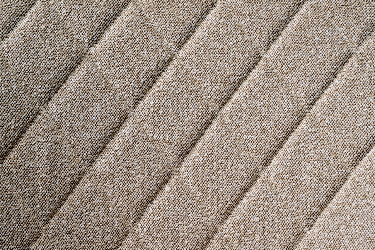 Nahaufnahme des beige strukturierten Stoffes eines Drehstuhlsitzes in diagonaler Perspektive