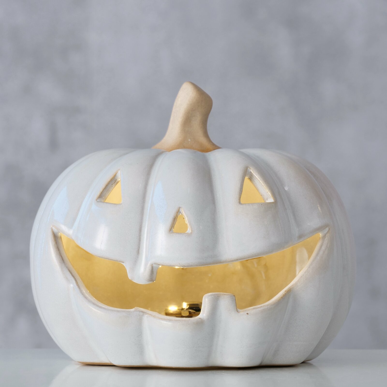 Keramik Kürbis mit lachendem Gesicht, frontal fotografiert, mit leuchtendem Inneren.