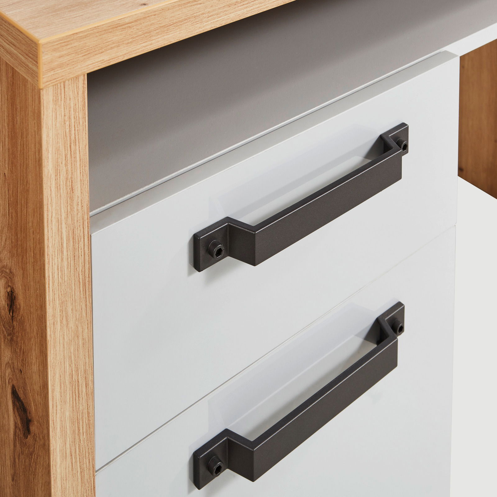 Nahaufnahme eines Schreibtisches mit zwei weißen Schubladen und schwarzen Griffen, seitliche Perspektive