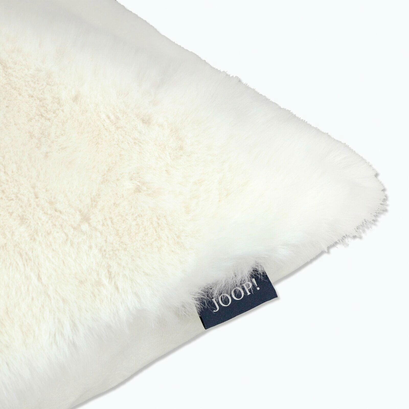 Nahaufnahme eines flauschigen weißen Kissens mit einem JOOP!-Label an der Seite.