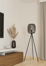 Moderne Stehleuchte ROMAZZINA mit schwarzem, dreibeinigem Gestell und offenem Lampenschirm aus Metallstreben, seitliche Perspektive im Wohnzimmer.