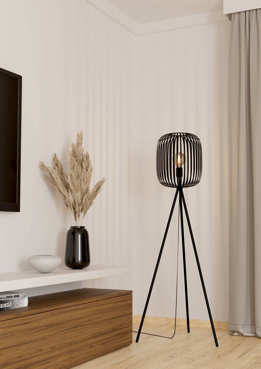 Moderne Stehleuchte ROMAZZINA mit schwarzem, dreibeinigem Gestell und offenem Lampenschirm aus Metallstreben, seitliche Perspektive im Wohnzimmer.