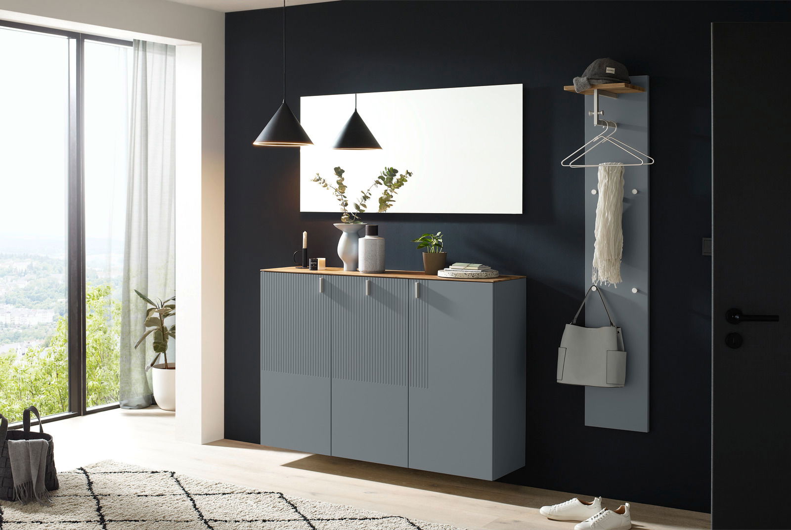 Moderner Eingangsbereich mit grauem Hängeschuhschrank, großem rechteckigen Spiegel und Garderobenpaneel, seitliche Perspektive.