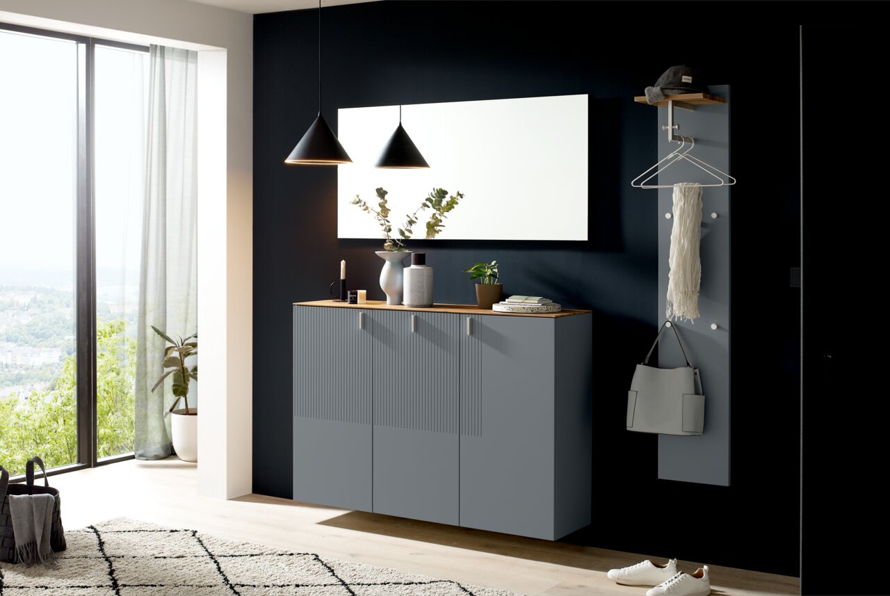 Moderner Eingangsbereich mit grauem Hängeschuhschrank, großem rechteckigen Spiegel und Garderobenpaneel, seitliche Perspektive.