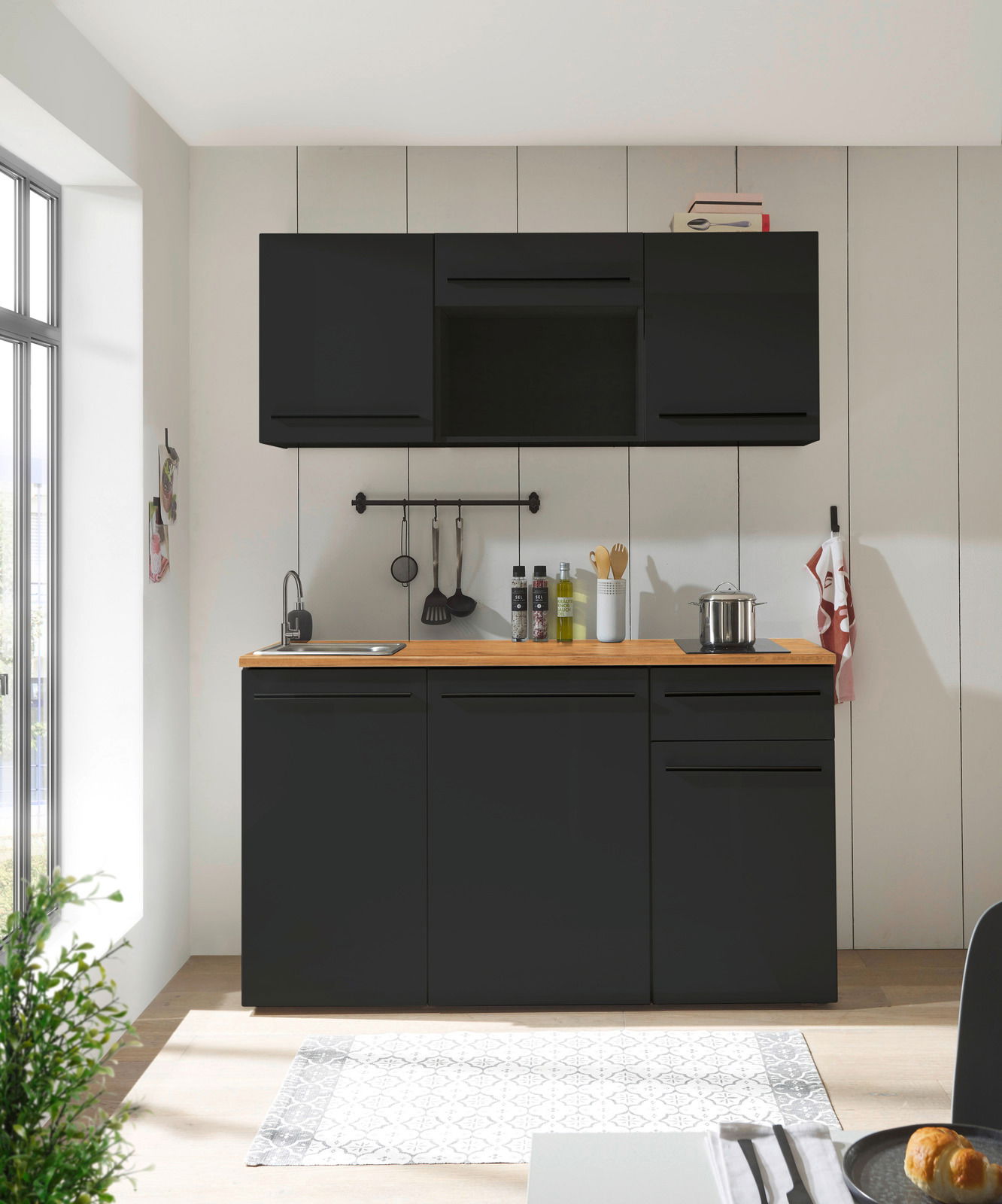 Moderne Single-Küche 160 cm ohne Elektrogeräte in schwarzem Design, frontal fotografiert, mit Holzarbeitsplatte, Spüle und Hängeschränken.
