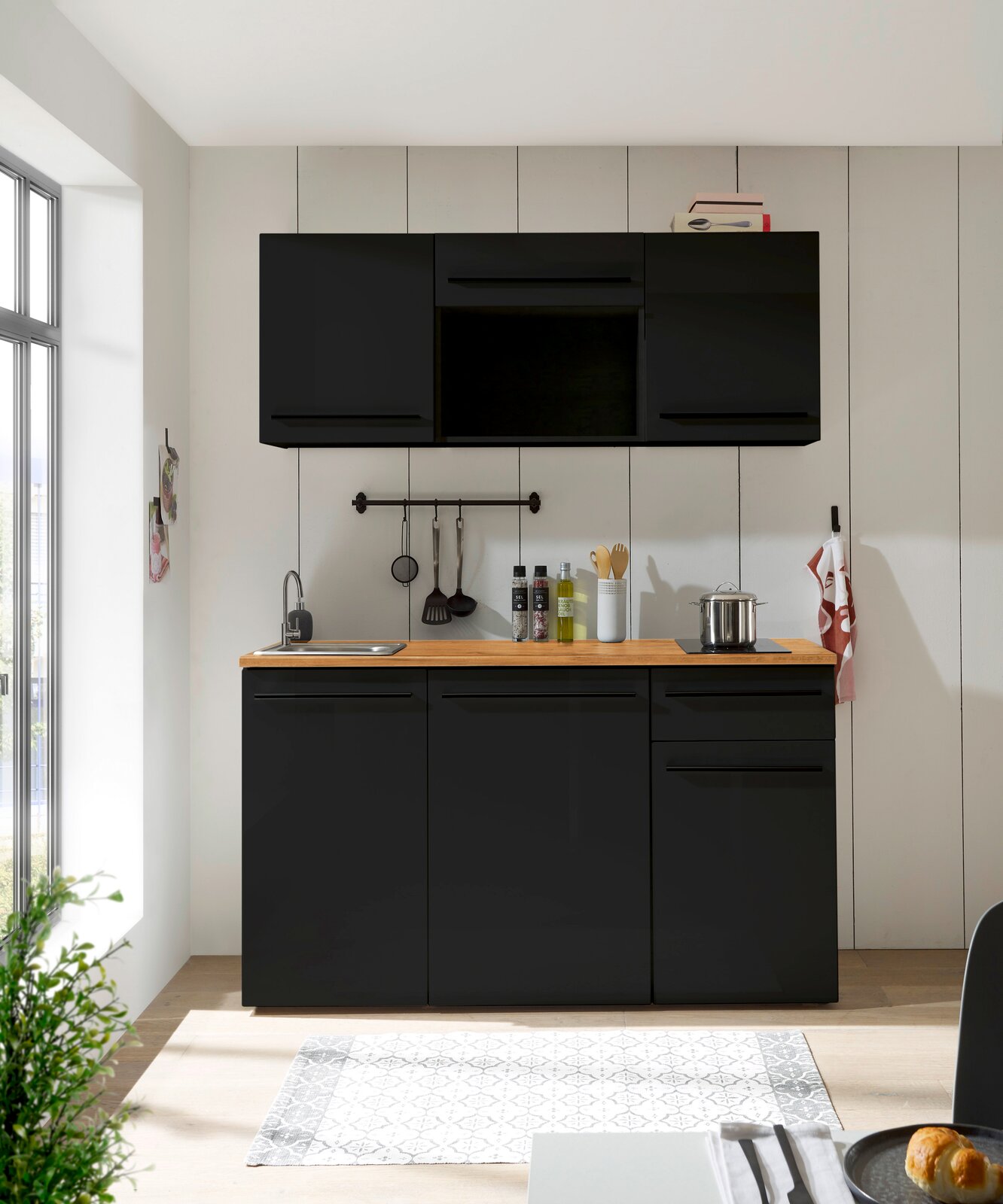 Moderne Single-Küche 160 cm ohne Elektrogeräte in schwarzem Design, frontal fotografiert, mit Holzarbeitsplatte, Spüle und Hängeschränken.