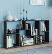 Modernes schwarzes Regal mit asymmetrischen Fächern, gefüllt mit Büchern und DVDs, dekoriert mit weißen Vasen und Kerzenhaltern; Frontansicht in leichter Perspektive von links vor hellblauer Wand.