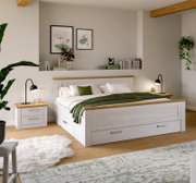 Modernes Schlafzimmer mit weißem Holzbett mit Schubladen und Eiche-Akzenten, grünem Plaid und Nachttischen; Perspektive: frontale Ansicht leicht von links.