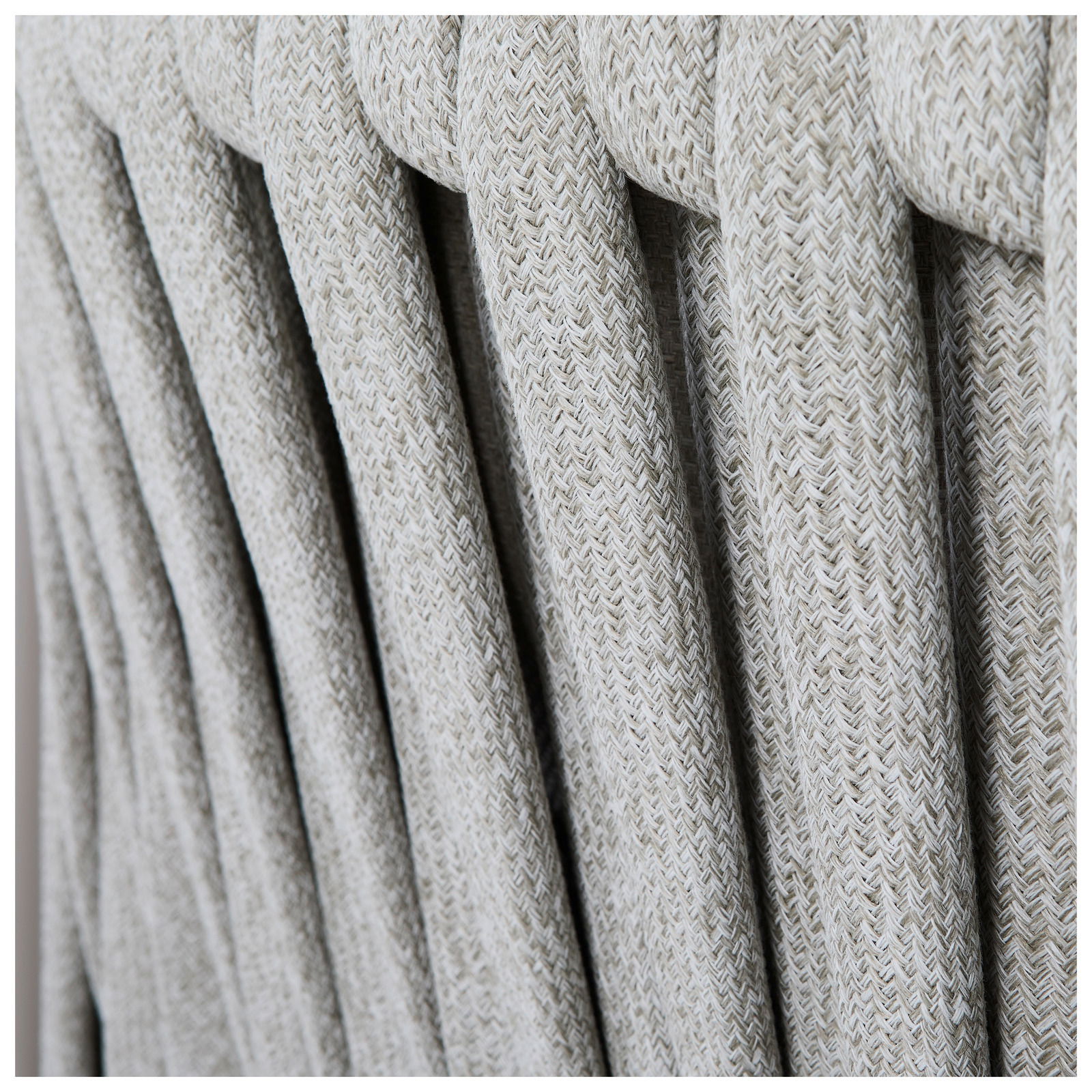 Nahaufnahme der geflochtenen Textur einer Loungegarnitur aus hellgrauem Material, seitliche Perspektive.