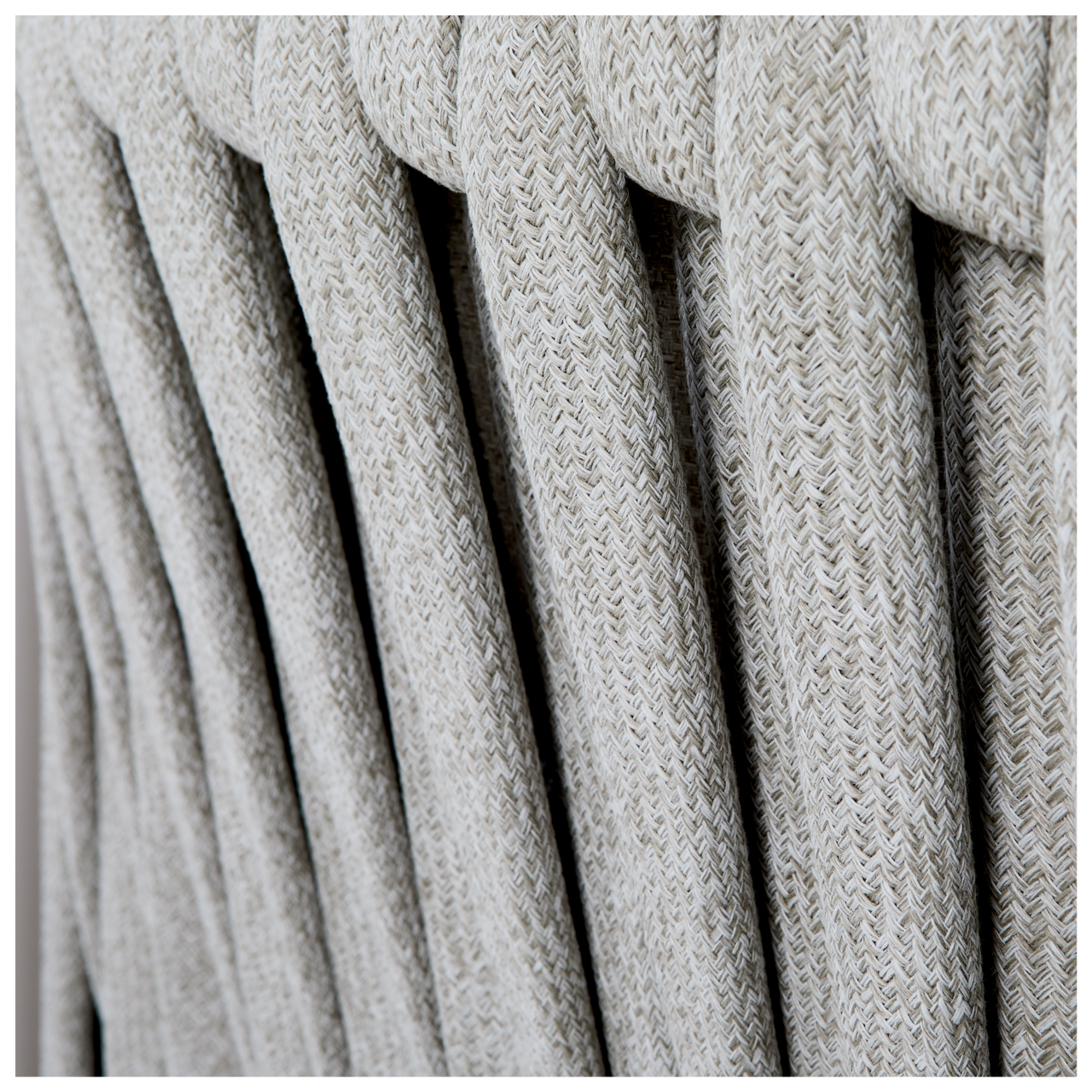Nahaufnahme der geflochtenen Textur einer Loungegarnitur aus hellgrauem Material, seitliche Perspektive.