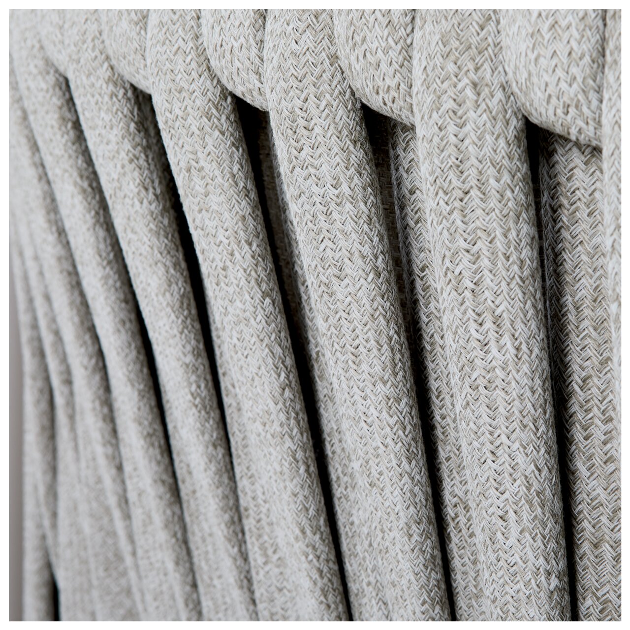 Nahaufnahme der geflochtenen Textur einer Loungegarnitur aus hellgrauem Material, seitliche Perspektive.