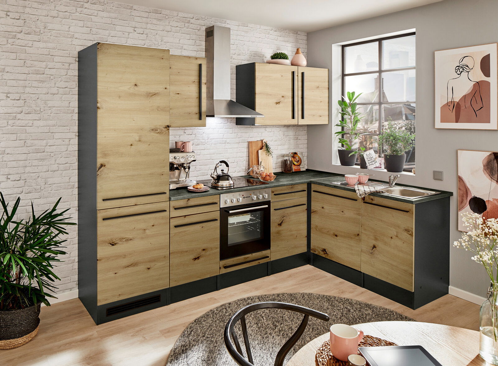 Moderne Küche mit Eckunterschrank in Holzoptik, fotografiert aus einer leicht erhöhten Perspektive. Die Küche verfügt über einen Herd, eine Spüle und mehrere Schränke mit schwarzen Griffen. Ein Fenster lässt Tageslicht herein und Pflanzen sowie Dekoration