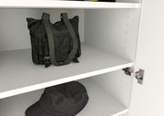 Innenansicht eines weißen Garderobenschranks mit zwei Regalböden, auf denen eine schwarze Tasche und ein schwarzer Hut liegen. Perspektive von schräg vorne.