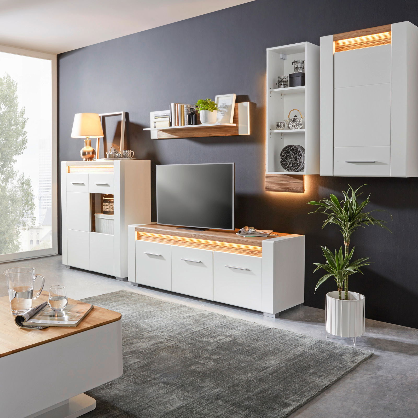 Modernes Wohnzimmer mit weißem TV-Unterteil, umgeben von stilvollen Möbeln und Dekorationen, seitliche Perspektive.