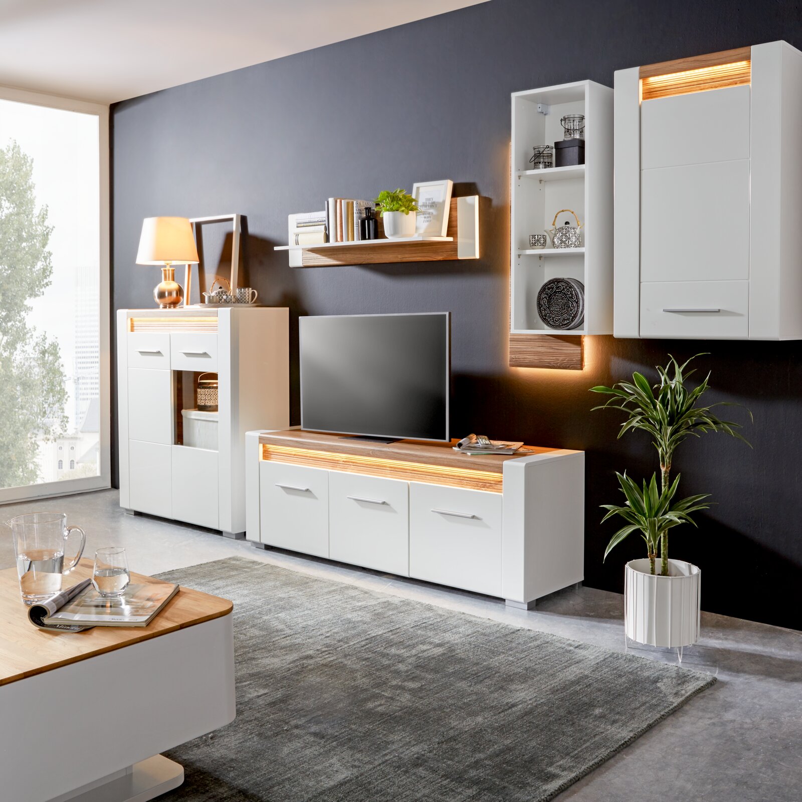 Modernes Wohnzimmer mit weißem TV-Unterteil, umgeben von stilvollen Möbeln und Dekorationen, seitliche Perspektive.