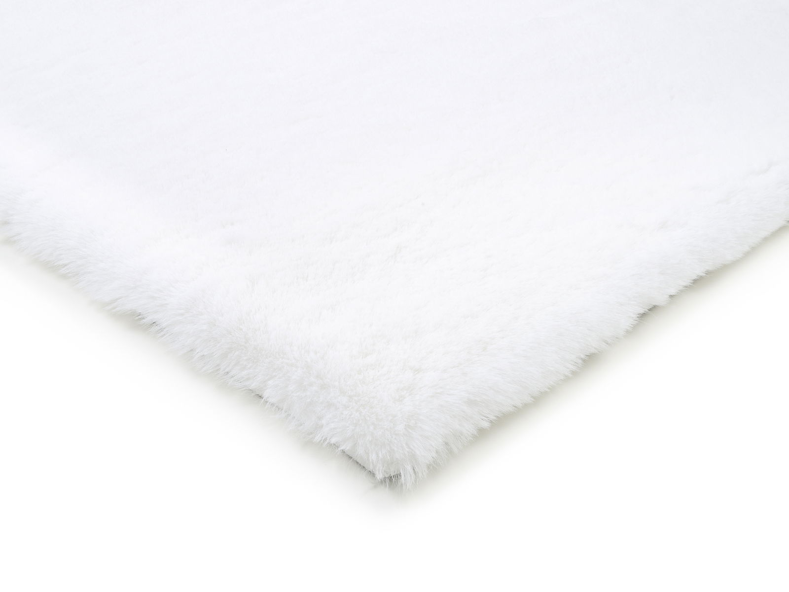 Nahaufnahme eines weißen Fellteppichs aus der Vogelperspektive, der die weiche Textur und die flauschigen Kanten zeigt.