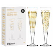 Zwei elegante Champagnergläser mit goldenen Verzierungen, eines mit Noten und das andere mit Herzmotiven, vor einer Verpackung mit der Aufschrift 'Ritzenhoff'. Frontalansicht.
