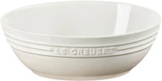 Weiße Keramikschüssel mit eingeprägtem „Le Creuset“-Schriftzug und umlaufenden Rillen, freigestellt vor weißem Hintergrund, seitliche Ansicht mit leichtem Blick von oben