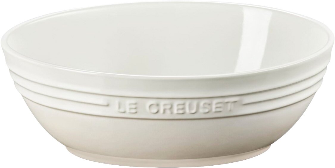 Weiße Keramikschüssel mit eingeprägtem „Le Creuset“-Schriftzug und umlaufenden Rillen, freigestellt vor weißem Hintergrund, seitliche Ansicht mit leichtem Blick von oben