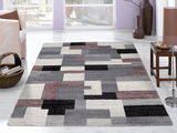 Moderner Frisé-Teppich mit geometrischem Muster in Grau-, Schwarz- und Rottönen, in einem hellen Wohnzimmer mit Blick auf den Teppich von oben.