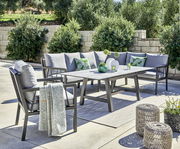 Garten-Lounge-Set mit grauen Kissen und Tisch, umgeben von Pflanzen, aus seitlicher Perspektive fotografiert.