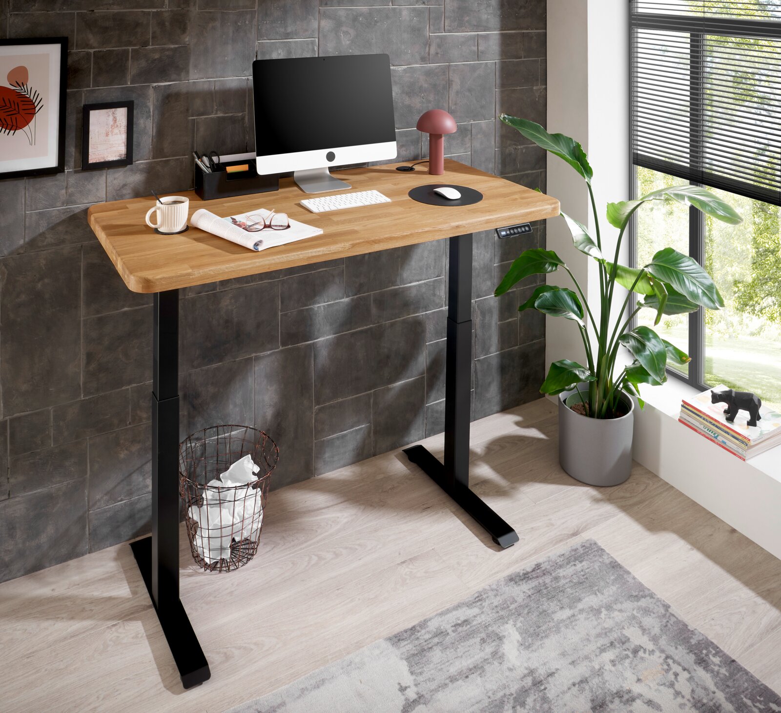 Moderner höhenverstellbarer E-Schreibtisch mit Holzplatte und schwarzem Gestell, seitliche Perspektive, ausgestattet mit Computer, Lampe und Pflanzen.
