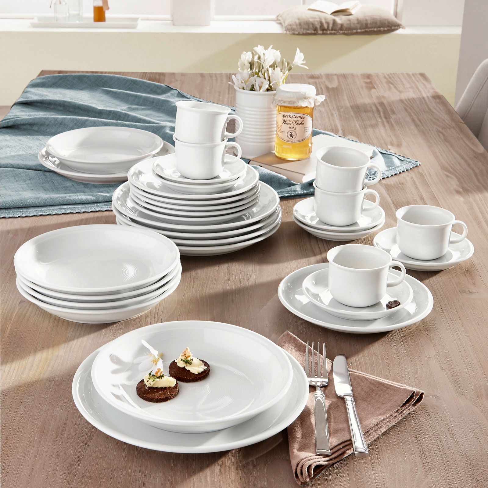 Kombiservice Trend weiß 30-tlg auf einem Tisch arrangiert, mit Tellern, Tassen und Besteck, aus einer leicht erhöhten Perspektive fotografiert.