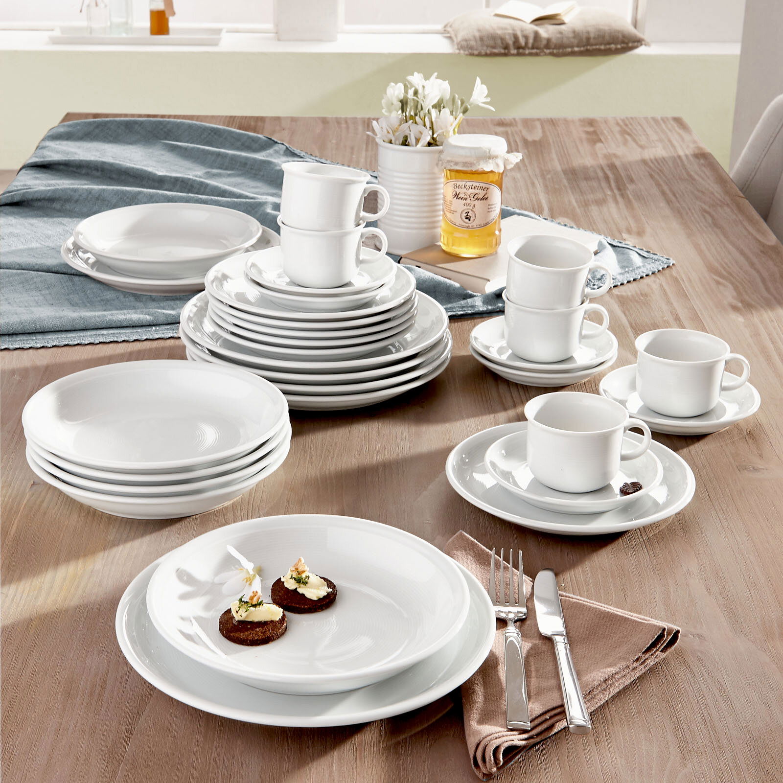 Kombiservice Trend weiß 30-tlg auf einem Tisch arrangiert, mit Tellern, Tassen und Besteck, aus einer leicht erhöhten Perspektive fotografiert.