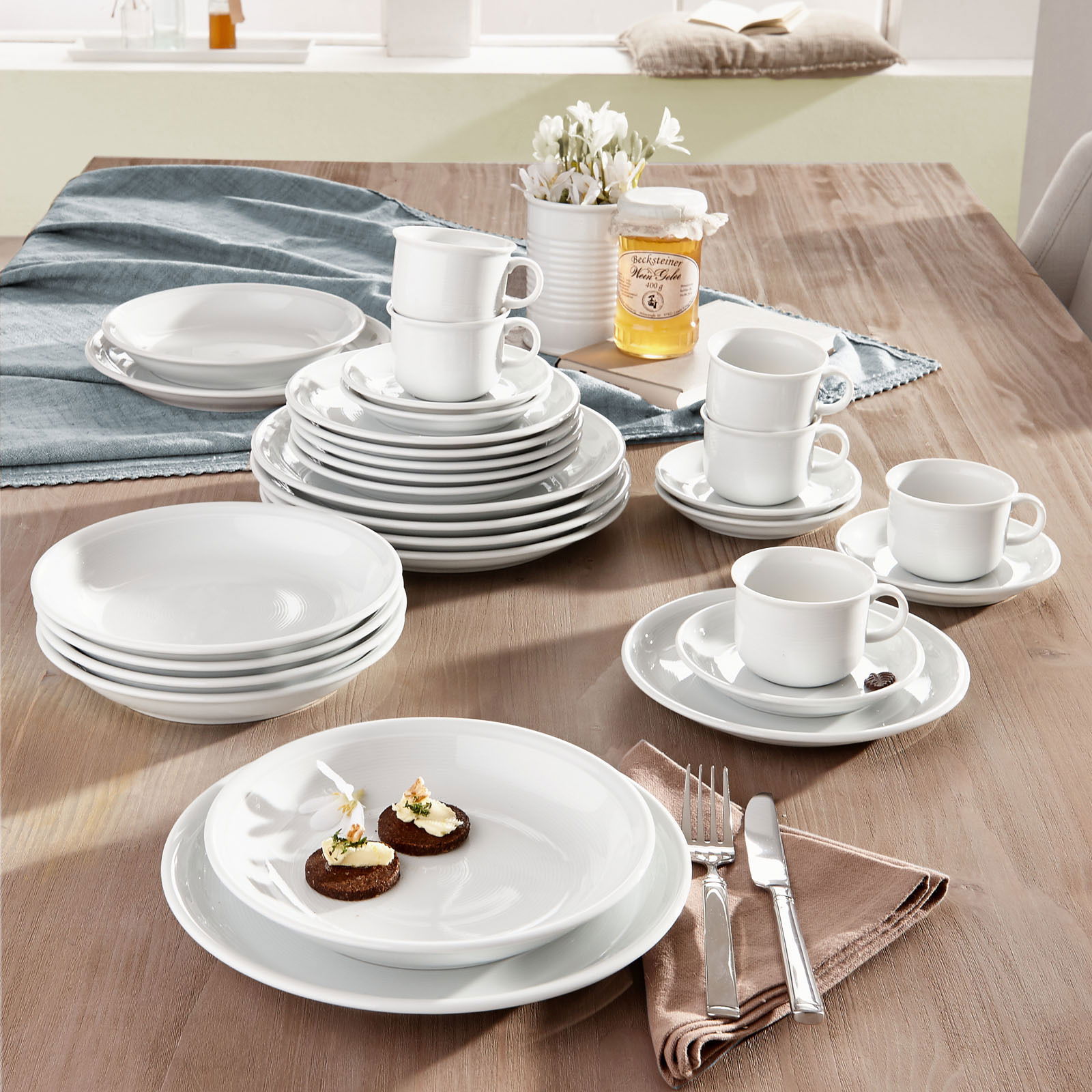 Kombiservice Trend weiß 30-tlg auf einem Tisch arrangiert, mit Tellern, Tassen und Besteck, aus einer leicht erhöhten Perspektive fotografiert.
