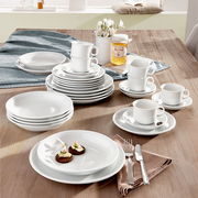 Kombiservice Trend weiß 30-tlg auf einem Tisch arrangiert, mit Tellern, Tassen und Besteck, aus einer leicht erhöhten Perspektive fotografiert.